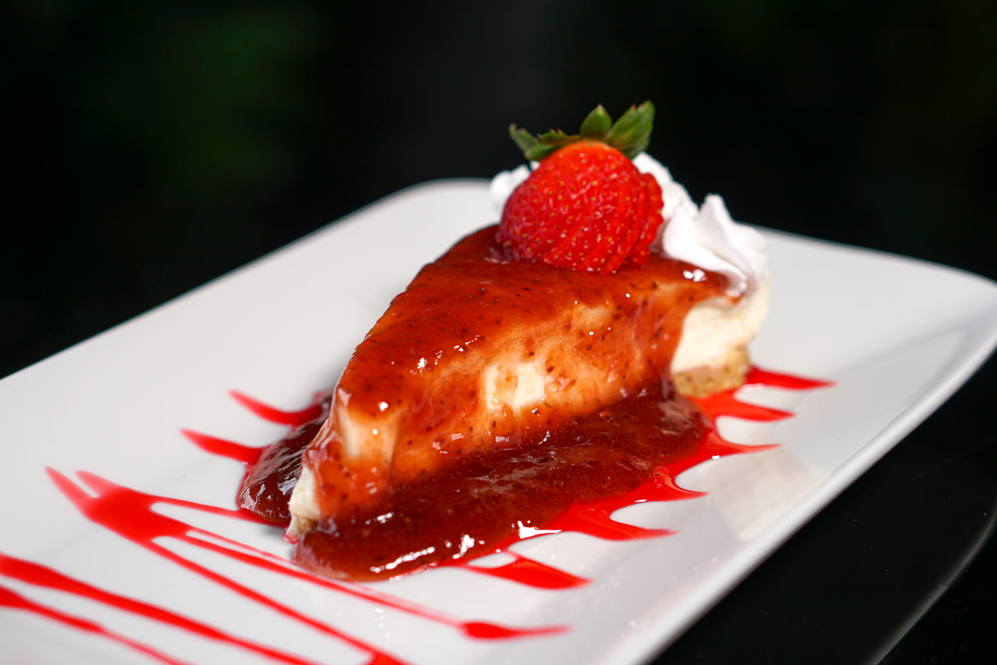 Fatia de cheesecake com calda de frutas vermelhas e morango
