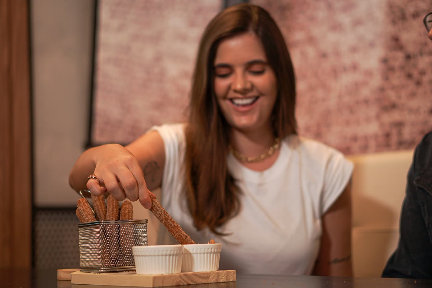Cliente sorrindo enquanto mergulha um churro no doce de leite