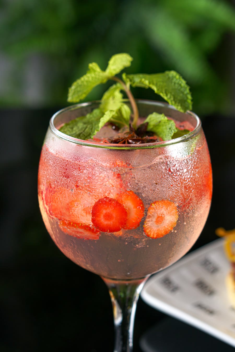 Gin com morango, hortelã e anis-estrelado em taça suada