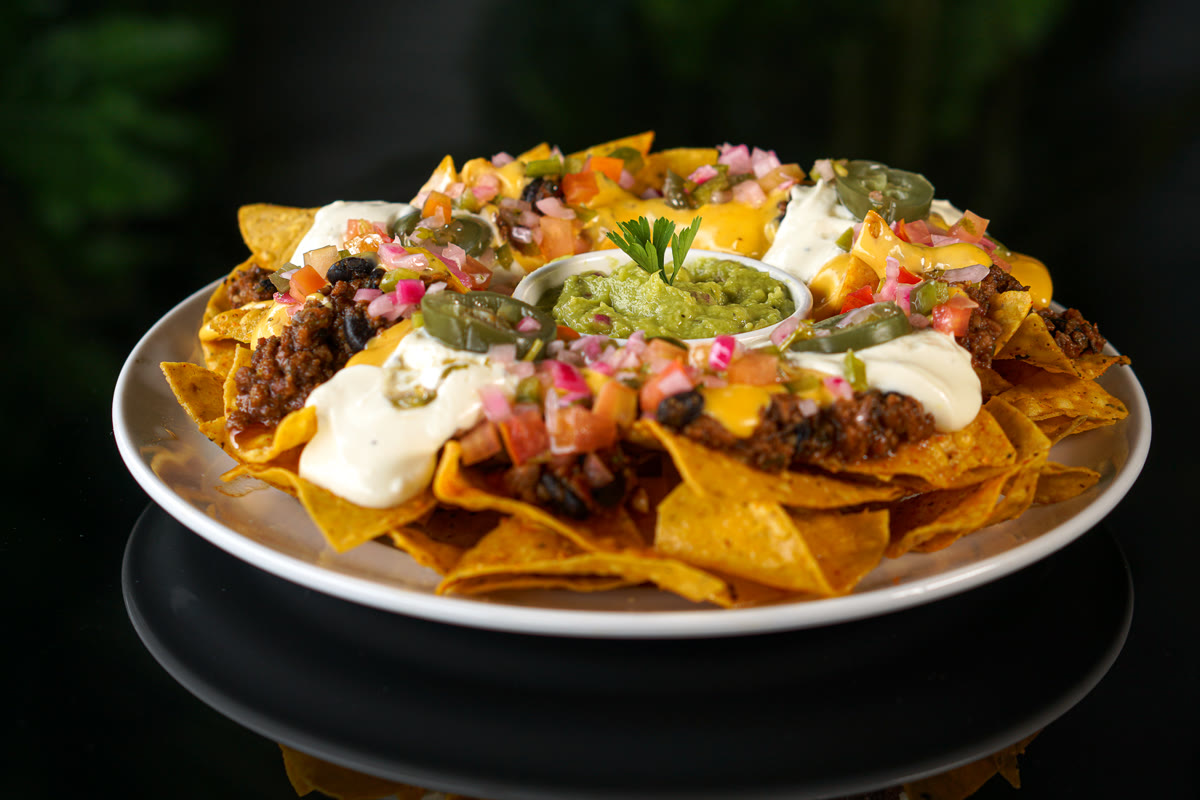 Nachos com chili beans, nacho cheese, sour cream, guacamole e jalapeño